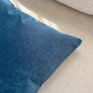 May include: A soft, blue velvet pillow cover. The cover is made of a plush, velvety fabric and has a smooth, even texture.