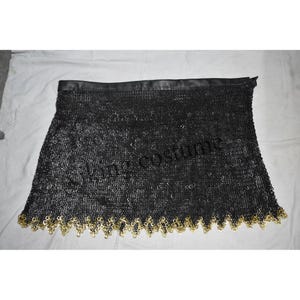 May include: Black chainmail skirt with a gold trim. The skirt is made of interlocking metal rings and has a leather waistband.