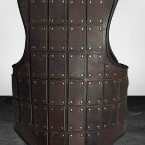 May include: A brown leather vest with a grid pattern of square leather plates, each secured with metal rivets.