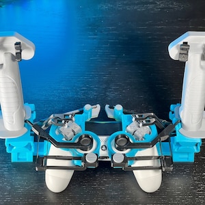 May include: A white and black video game controller with two blue and white attachments on the top. The attachments are designed to be held by the hands and have buttons on the top.