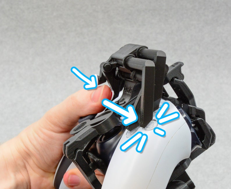 Puede incluir: Un accesorio de mando negro de pl&aacute;stico con una palanca que se puede mover para presionar los botones de un mando de videojuego blanco. El accesorio est&aacute; dise&ntilde;ado para ayudar a las personas con movilidad limitada de las manos a jugar a videojuegos.