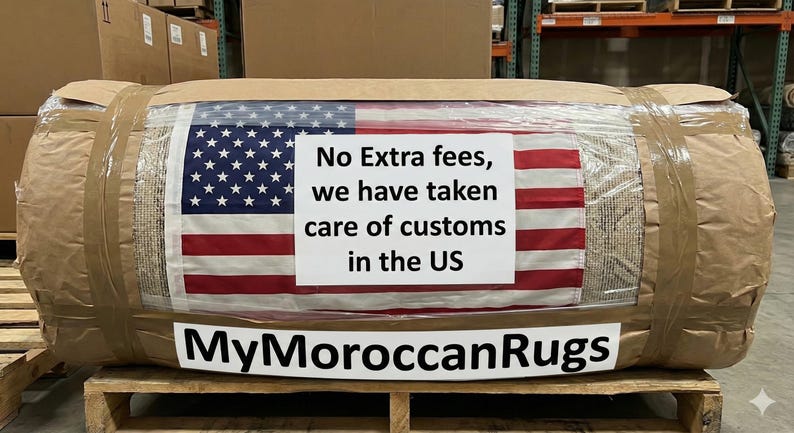 K&ouml;nnte beinhalten: Ein gerollter Teppich, verpackt in braunem Papier und durchsichtigem Kunststoff, mit Klebeband befestigt. Die amerikanische Flagge ist auf dem Teppich zu sehen, mit einem Schild mit der Aufschrift "No Extra fees, we have taken care of customs in the US." Der Markenname "MyMoroccanRugs" wird angezeigt.