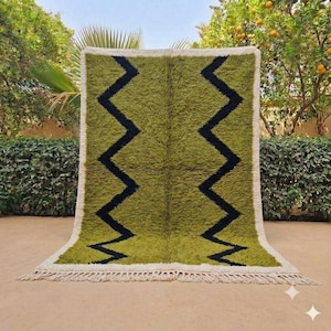 May include: A rectangular area rug featuring a deep olive green pile with two prominent black zigzag lines running vertically down the centre. The rug is framed by a thick white border and finished with a fringed edge along the bottom side.