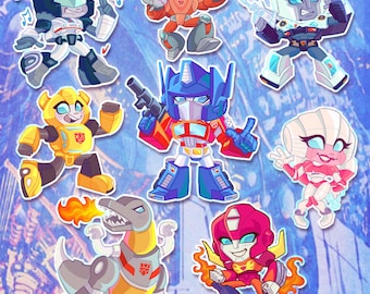 Może przedstawiać: Zestaw ośmiu kreskówkowych postaci Transformersów, w tym Optimus Prime, Bumblebee, Starscream i Megatron. Postacie są w różnych pozach i z różnymi wyrażeniami twarzy, niektóre trzymają broń lub instrumenty muzyczne. Tło to kolorowy abstrakcyjny wzór.