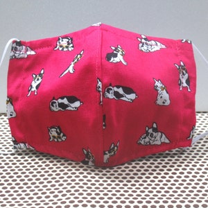 Op de afbeelding: Een roze gezichtsmasker met een wit elastiek. Het masker heeft een herhalend patroon van zwarte en witte Franse Bulldogs die een zonnebril dragen.