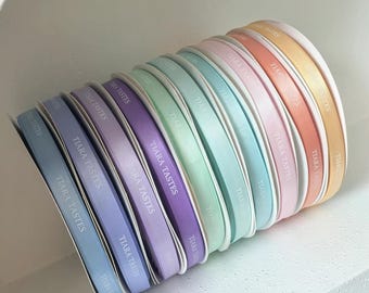 May include: A stack of pastel colored satin ribbon spools with the text "TIARA TASTES" printed on each spool.