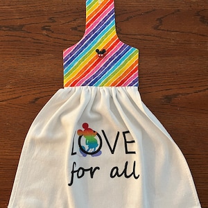 May include: White kitchen towel with a rainbow striped hanging loop and the text "LOVE for all" with a rainbow Mickey Mouse graphic.