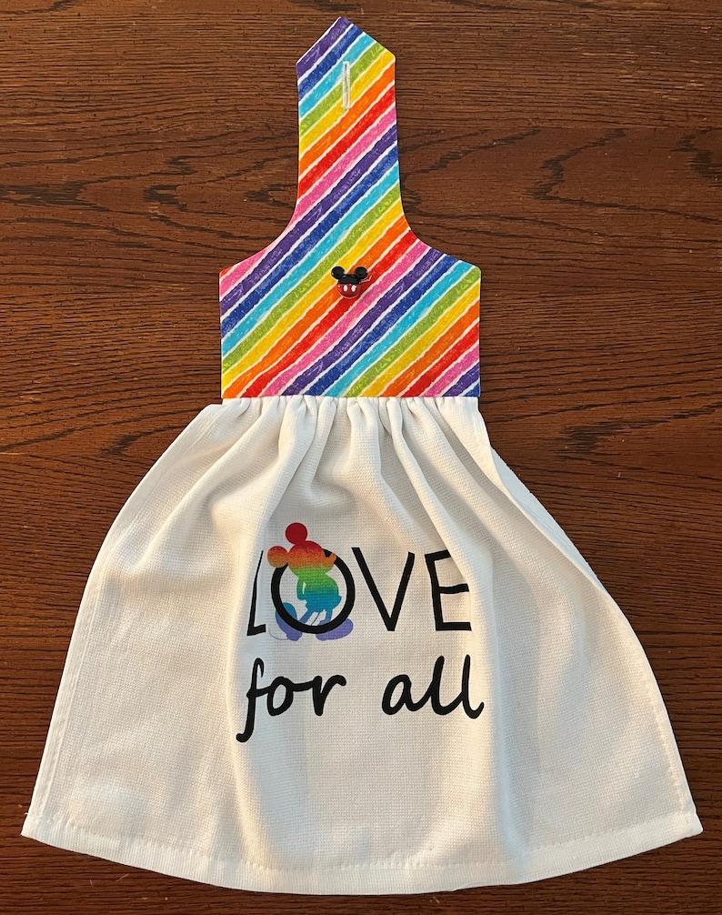 May include: White kitchen towel with a rainbow striped hanging loop and the text "LOVE for all" with a rainbow Mickey Mouse graphic.