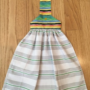 May include: A white kitchen towel with green and gray stripes. The towel has a colorful striped hanging loop with yellow buttons.