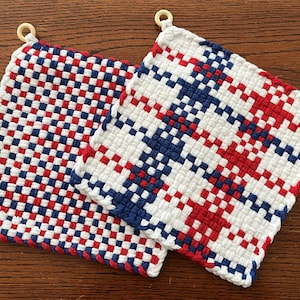 May include: Two red, white, and blue woven pot holders with wooden rings. The pot holders have a checkered pattern.