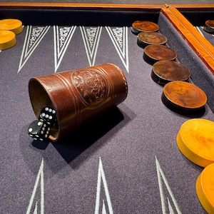 以下が含まれることがあります： ダークパープルのゲーム盤、木製のフレーム、茶色の革製サイコロカップを備えたバックギャモンセット。 茶色と黄色の木製ゲームピースと黒いサイコロが含まれています。