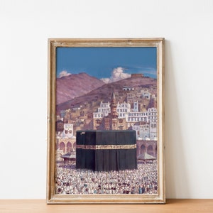 May include: A framed painting depicting the Kaaba, a cube-shaped building in Mecca, Saudi Arabia. The Kaaba is surrounded by a large crowd of people, and the painting also shows a view of the surrounding city and mountains.