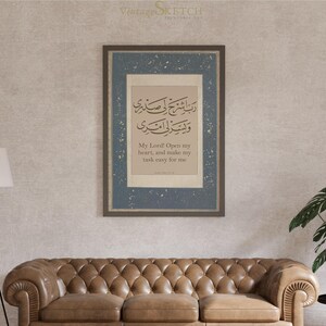 May include: A framed print with a blue background and a white border. The print features Arabic calligraphy and the text "My Lord Open my heart, and make my task easy for me".