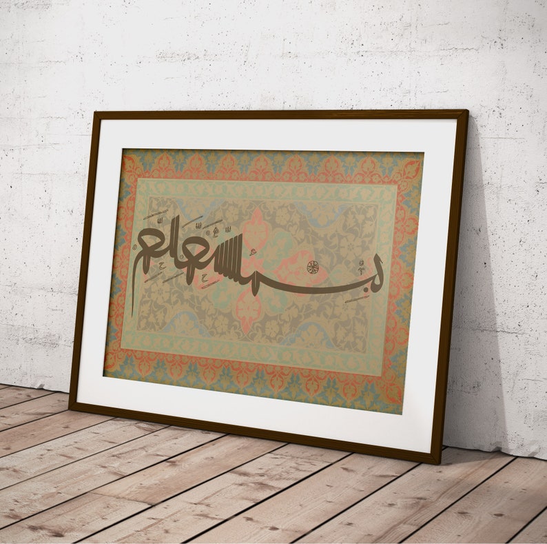 May include: A framed print of Islamic calligraphy in brown ink on a beige background with a colorful floral pattern border. The calligraphy reads "Allah" in Arabic.