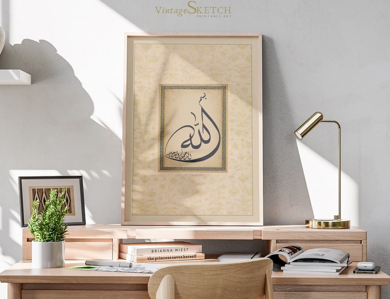 Pu&ograve; includere: Una stampa incorniciata con uno sfondo beige e una cornice dorata. La stampa presenta un design di calligrafia in bianco e nero della parola araba "Allah" in un quadrato con un bordo dorato. La stampa &egrave; appesa a un muro sopra una scrivania con una lampada, libri e una pianta in vaso.