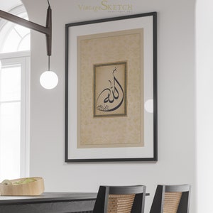 Pu&ograve; includere: Una stampa incorniciata nera con uno sfondo beige e un design di calligrafia nera della parola "Allah" in una cornice dorata. La stampa &egrave; appesa a una parete bianca in un interno moderno.