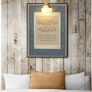 May include: A framed print with a blue background and gold accents. The print features Arabic calligraphy and the text "My Lord! Open my heart, and make my task easy for me".
