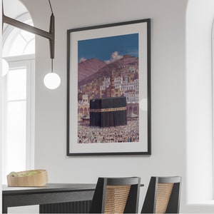 May include: A framed photograph of a mosque with a large crowd of people in front of it. The mosque is a large, white building with a black dome. The crowd is made up of people of all ages and genders. The photograph is taken from a high angle, looking down on the mosque and the crowd.