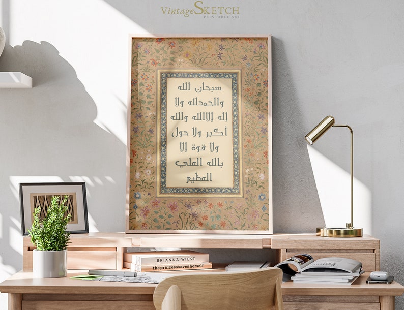 May include: A framed print with a beige background and a floral border. The print features Arabic calligraphy in black and gold, with the text "سبحان الله والحمد لله ولا إله إلا الله والله أكبر ولا حول ولا قوة إلا بالله العلي العظيم".