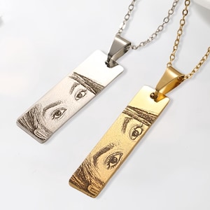 May include: Two silver and gold necklaces with rectangular pendants featuring engraved portraits.