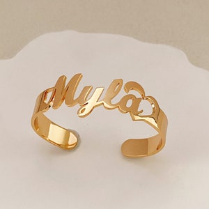 May include: Gold-toned name bracelet with the name "Myla" and a heart cutout.