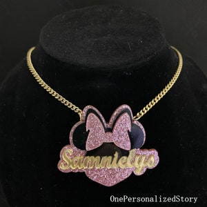 Op de afbeelding: Een gouden ketting met een roze en zwarte glitter Minnie Mouse hanger. De hanger heeft de naam "Sammielys" in gouden glitter letters.