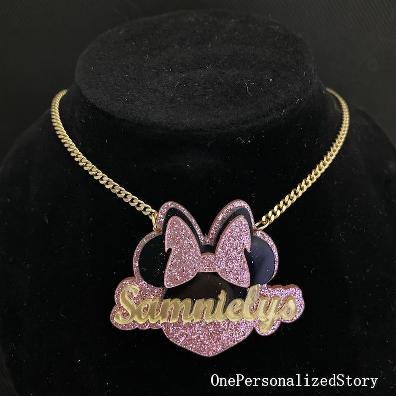 Op de afbeelding: Een gouden ketting met een roze en zwarte glitter Minnie Mouse hanger. De hanger heeft de naam "Sammielys" in gouden glitter letters.