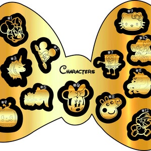 K&ouml;nnte beinhalten: Eine goldfarbene Schleife mit 12 Schwarzwei&szlig;-Charakterillustrationen. Die Charaktere umfassen Mickey Mouse, Minnie Mouse, Hello Kitty, SpongeBob Schwammkopf, ein Einhorn, einen L&ouml;wen, einen Marienk&auml;fer, einen K&uuml;rbis, ein Schwein, einen Pilz, eine Meerjungfrau und Mario.