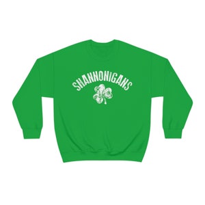 Può includere: Felpa verde con un trifoglio bianco e il testo "SHANNONIGANS" in un font bianco usurato.
