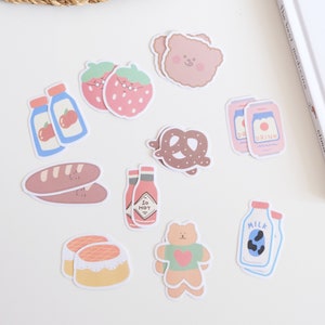 May include: A set of 10 cute and colorful stickers featuring various food and drink items, including a bear, pretzels, strawberries, milk, juice, and hot sauce. The stickers are perfect for adding a touch of whimsy to planners, journals, laptops, and more.