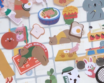 May include: A set of colorful stickers featuring various illustrations, including animals, food, and objects. The stickers are perfect for adding a touch of whimsy to planners, journals, and other items. Some of the stickers feature text, such as "I like week end" and "M'hello".