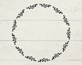 May include: A black and white wreath with a simple heart and leaf design. The wreath is circular and has a rustic wood background.