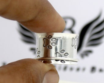 May include: Silver ring with a design of paw prints around the band.