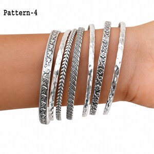 Detailed view of handmade silver bangle designs, including floral, leaf, elephant, wave, and oxidized pattern details.