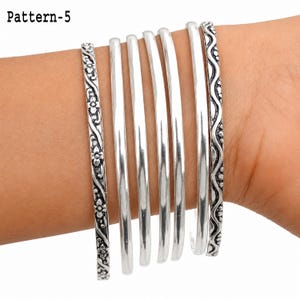 Stackable sterling silver bracelet set shown against a clean white background, with each thin bangle design clearly visible.