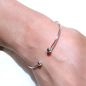 May include: A silver bangle bracelet with two round ball accents.