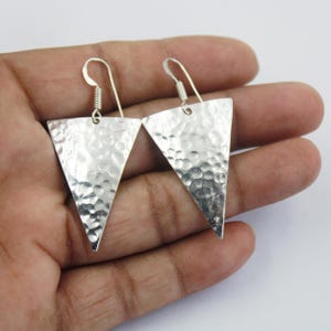 May include: A pair of silver triangle earrings with a hammered texture.