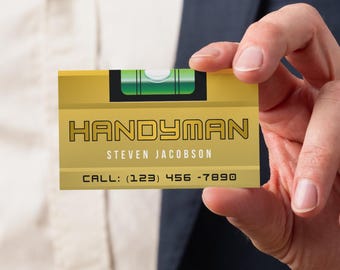 May include: A gold business card with the word "HANDYMAN" in bold, black letters. The card features a level tool graphic and the name "STEVEN JACOBSON" below. The phone number is (123) 456-7890.