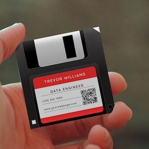 May include: A black floppy disk business card with a red and white label. The label includes the name "Trevor Williams", the title "Data Engineer", a phone number, a website address, and a QR code.