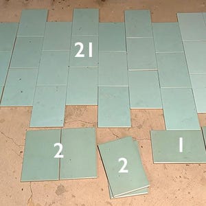 May include: Arrangement of light green rectangular tiles, some with white numbers, laid out on a brown surface. The numbers include 1, 2, 3, and 21, indicating quantity or order. The tiles are of varying sizes.