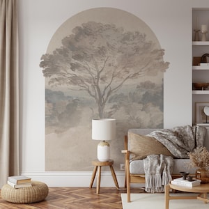 Può includere: Un murale a parete dai toni neutri raffigurante un albero in stile acquerello all'interno di una cornice ad arco. L'opera d'arte è il punto focale di un soggiorno, completato da una lampada bianca, mobili in legno ed elementi decorativi.
