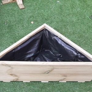 May include: A triangular wooden planter with a black liner. The planter is made of natural wood and has a rustic look.