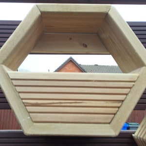 May include: A hexagonal wooden planter box with a slatted bottom. The planter is made of natural wood and has a rustic look.