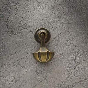 May include: A brass-toned metal drop pull handle featuring a circular backplate and a fan-shaped pendant. The hardware has a weathered, antique finish with visible vertical ridges on the lower section of the drop handle component.