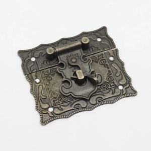Op de afbeelding: Antiek messing slot met een sierlijk ontwerp. Het slot heeft een decoratief scharnier en een vergrendelingsmechanisme.