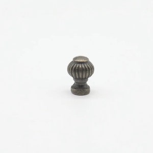 May include: A small, antique-style cabinet knob with a fluted, round design. The knob is made of metal and has a dark, aged finish.