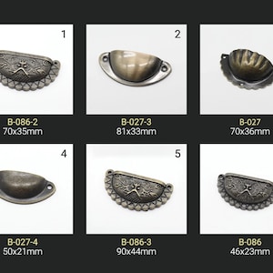 Pode incluir: Seis botões de armário de estilo antigo com designs ornamentados. Os botões são de metal e têm um acabamento desgastado. Os botões são etiquetados com o seu tamanho em milímetros. Os botões estão dispostos em duas filas de três.