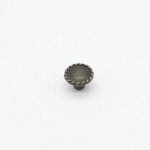 May include: A small, round, antique brass cabinet knob with a rope-like design around the edge.