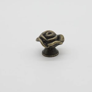 May include: A bronze-coloured rose-shaped cabinet knob with a round base.