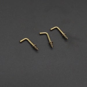 May include: Three gold-toned metal hooks with screw backs. The hooks are L-shaped and have a smooth finish.